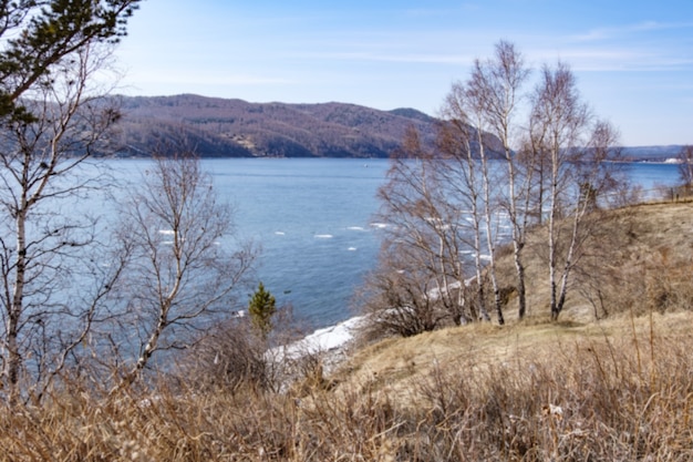 Onscherpe achtergrond Landschapsmening van het Baikalmeer met bomen en bergen op april in Kamen Cherskogo, Irkoetsk Oblast, Rusland