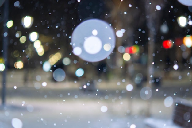 Onscherpe achtergrond Stadszicht lichten vallende sneeuw nacht straat bokeh vlekken van koplampen van bewegende ca