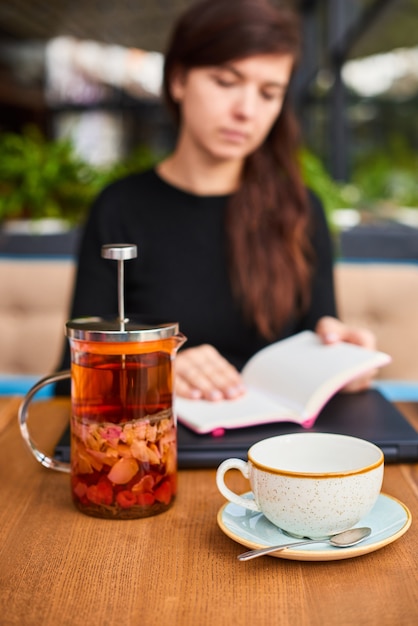 Onscherpe vrouw met notitieboekje en gezonde thee op zakenlunch