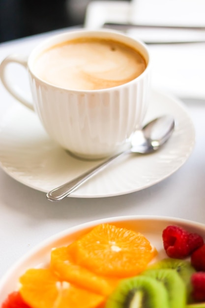 Ontbijt en luxe kopje koffie met melk en fruitschaal op de geserveerde tafel voor gastvrijheid en gastronomie