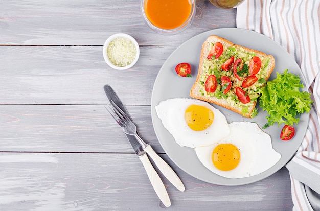 Ontbijt. Gebakken ei, groentesalade en een gegrilde avocadosandwich. Bovenaanzicht