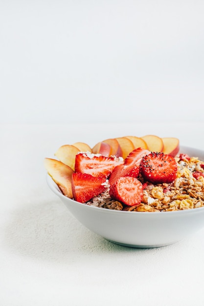 Ontbijt havermout granen granola met aardbeien en perzik op een witte plaat