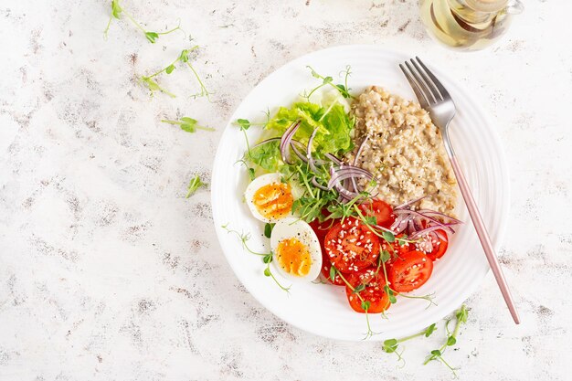 Ontbijt havermout pap met gekookte eieren en verse groenten Gezond evenwichtig eten Trendy eten Top view plat liggen
