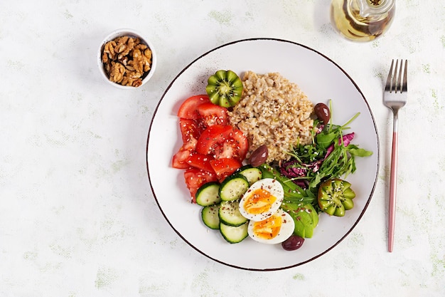 Ontbijt havermoutpap met gekookte eieren frisse salade en kiwi gezond uitgebalanceerd voedsel bovenaanzicht overhead