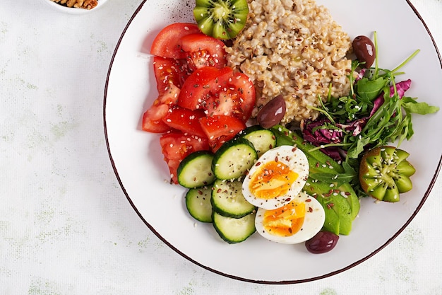 Ontbijt havermoutpap met gekookte eieren frisse salade en kiwi gezond uitgebalanceerd voedsel bovenaanzicht overhead