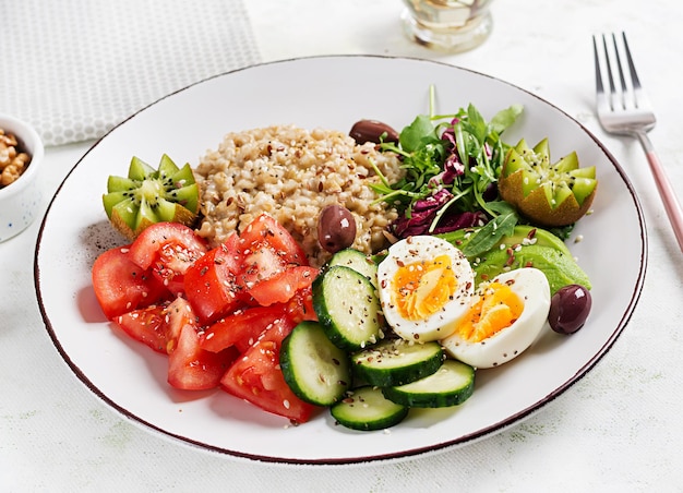 Ontbijt havermoutpap met gekookte eieren frisse salade en kiwi Gezond uitgebalanceerd voedsel