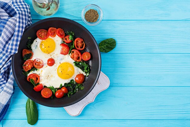 Ontbijt Ketogene dieetvoedsel Gebakken eieren spinazie en tomaten Keto paleo ontbijt Top view kopieerruimte