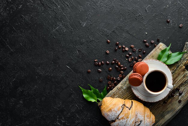 Ontbijt Koffiecroissant en bitterkoekjes Op een zwarte stenen achtergrond Bovenaanzicht Vrije ruimte voor uw tekst