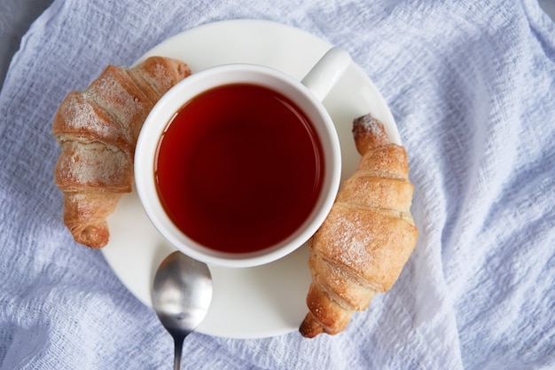 Ontbijt kopje thee en verse zelfgemaakte croissants op een wit servet, van bovenaf bekijken