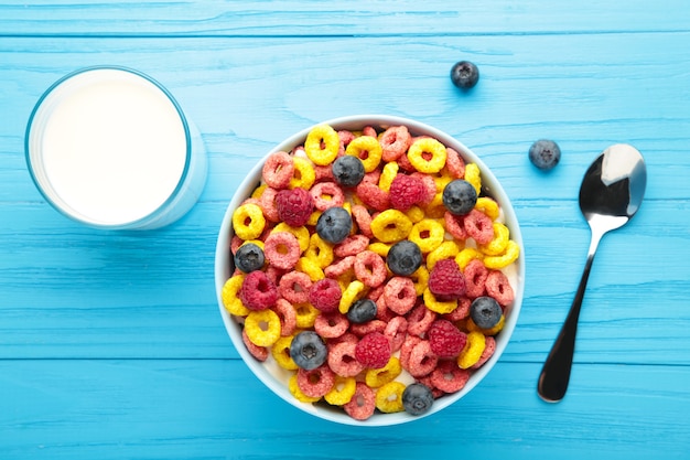 Ontbijt met cornflakes, melk en bessen op blauwe achtergrond. Bovenaanzicht. Verticale foto