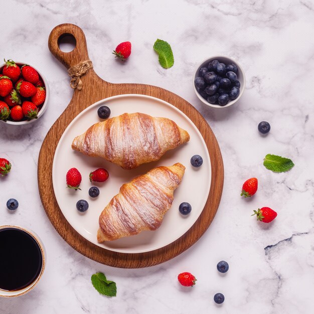 Ontbijt met croissants en vers fruit, bovenaanzicht.