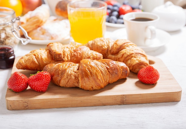 Ontbijt met croissants, koffie, sap, jam, ontbijtgranen en vers fruit