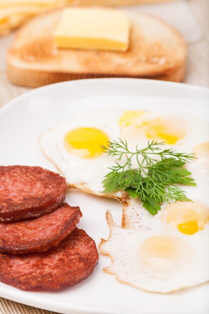 Ontbijt met gebakken eieren, worst en toast op plaat