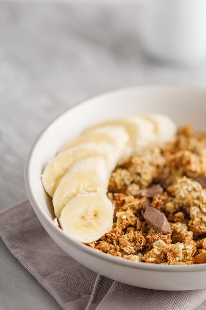 Ontbijt met granola met banaan. Stukjes chocolade en pot met muesli