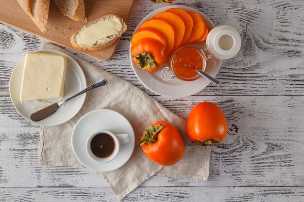 Ontbijt met kaki, potje jam op witte tafel