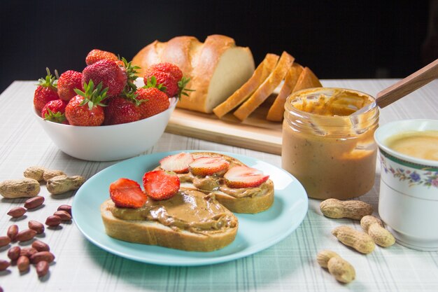 Ontbijt met koffie en broodjes met pindapasta en aardbeien