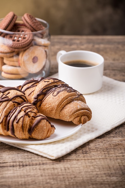 Ontbijt met koffiemelk en croissants op houten tafel