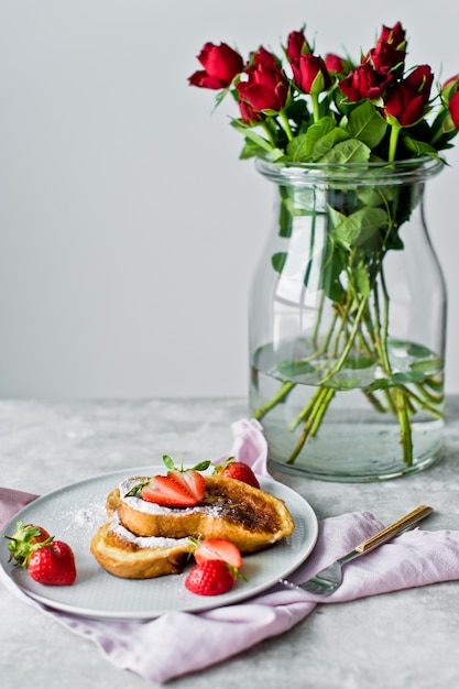 Ontbijt met wentelteefjes en aardbeien, een vaas met rode rozen.