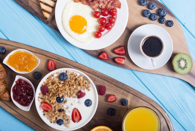 Ontbijt met yoghurt, eieren, bessensap, croissant en jam