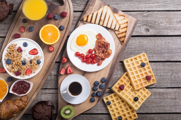 Ontbijt met yoghurt, eieren, bessensap, croissant en jam