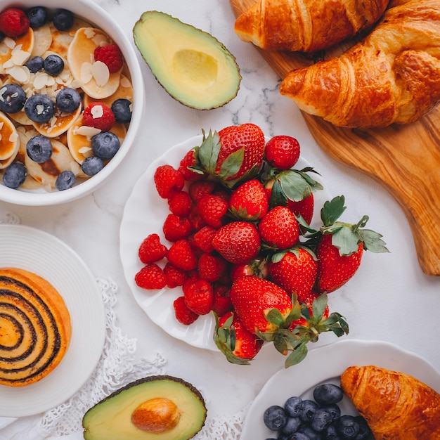 Ontbijt, Mini pannenkoeken met aardbeien, croissants en avocado, Heerlijk zomers eten, Bovenaanzicht op een marmeren achterkant