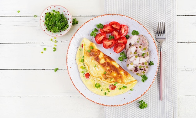 Ontbijt. Omelet met tomaten, kaas en vleesterrine of gehaktbrood op witte plaat. Frittata - Italiaanse omelet. Keto-dieet. Bovenaanzicht