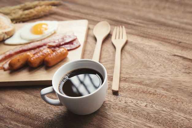 ontbijt omgeving met zwarte koffie en sauaage spek omelet op de houten tafel