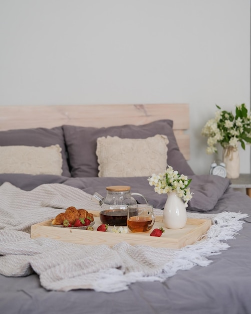 Ontbijt op bed Dienblad met theecroissant en aardbeien op het bed in de slaapkamer