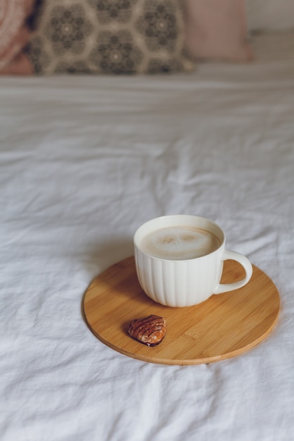 Ontbijt op bed. Een mok koffie, hartvormige koekjes, een houten dienblad. Vrouwendag. Knus.