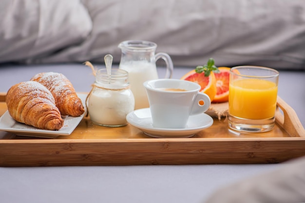 Ontbijt op bed met oranje fruit en gebak op een dienblad close-up