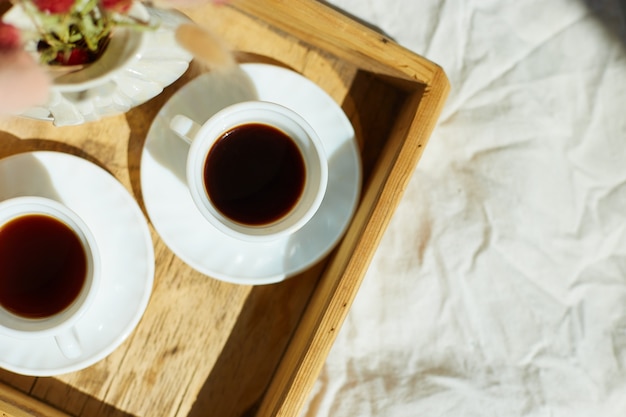 Ontbijt op bed, probeer met twee kopjes koffie en bloem in het zonlicht thuis, kamermeisje brengt dienblad met ontbijt in hotelkamer, goede service