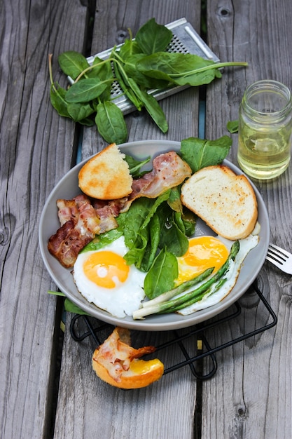 Ontbijt op een bord roerei met geroosterd brood, spek en aromatische kruiden