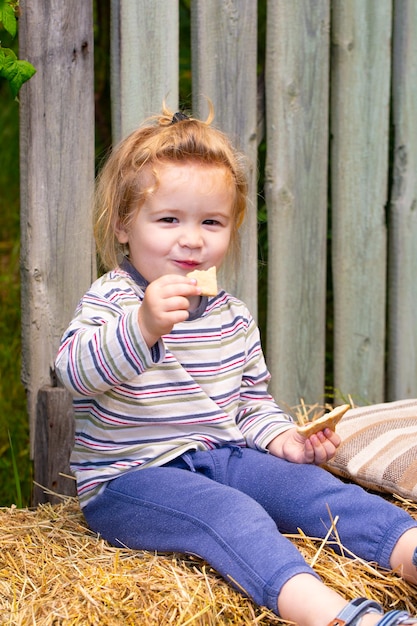 Ontbijt op hooiberg gelukkig jeugdportret kind meisje op natuur achtergrond cookies