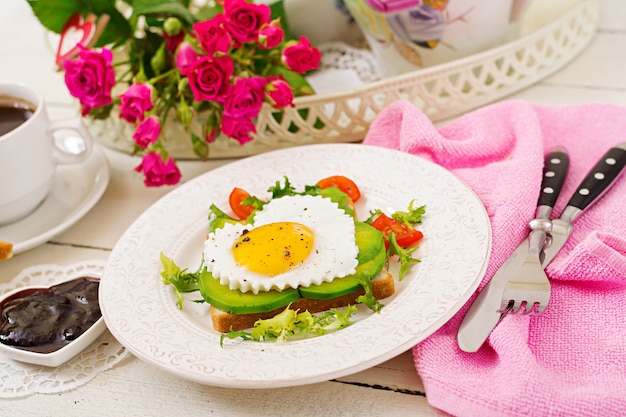 Ontbijt op Valentijnsdag - sandwich van gebakken ei in de vorm van een hart, avocado