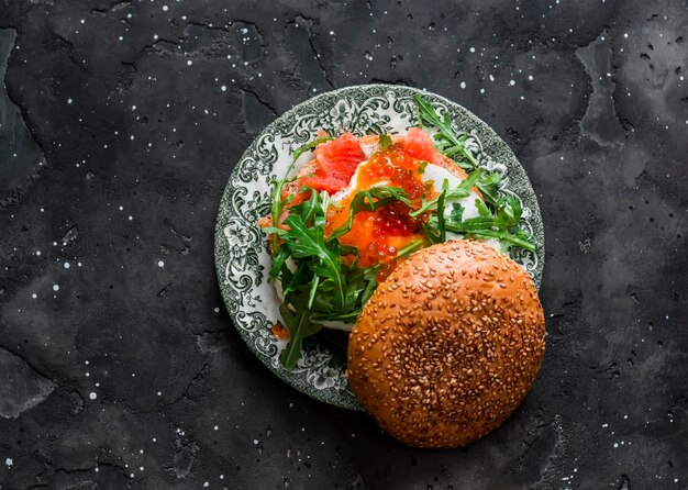 Ontbijt tapas snackburger met ei zalm rucola en rode kaviaar op een donkere achtergrond bovenaanzicht