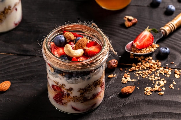 Ontbijt van verse natuurlijke yoghurt met zelfgemaakte muesli en bosbessen aardbei in glazen pot banner menu recept plaats voor tekst bovenaanzicht