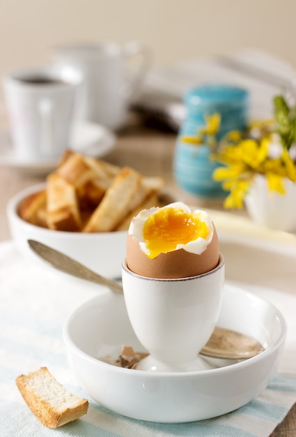 Ontbijt van zacht gekookt ei, broodtoast, koffie met room en verse krant.