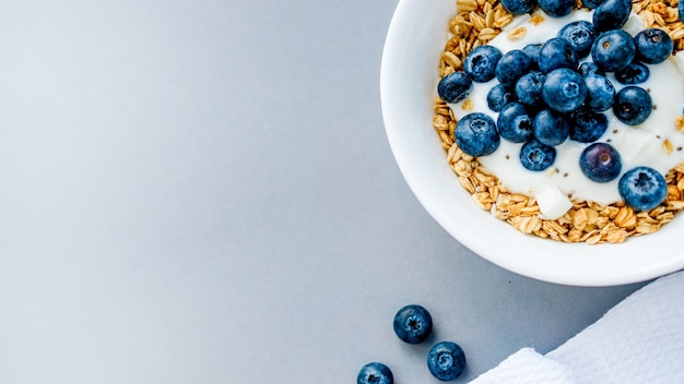 ontbijtgranola met ontbijtgranola met bosbessen op wit keukendoek op lichtgrijze achtergrond op een tafel