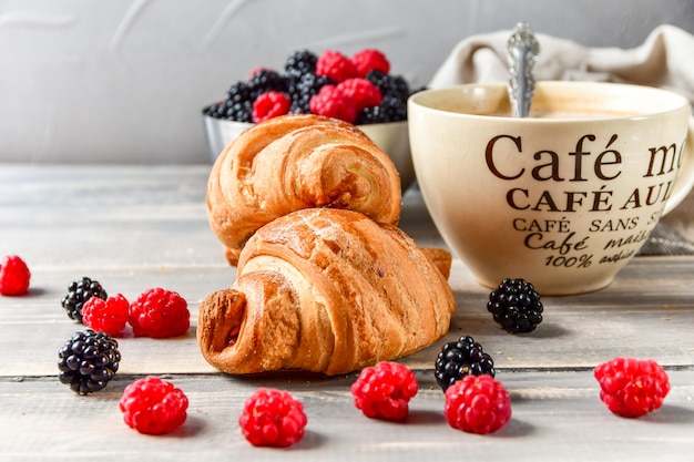 Ontbijtkoffie met melk en croissants en verse frambozen en bramen