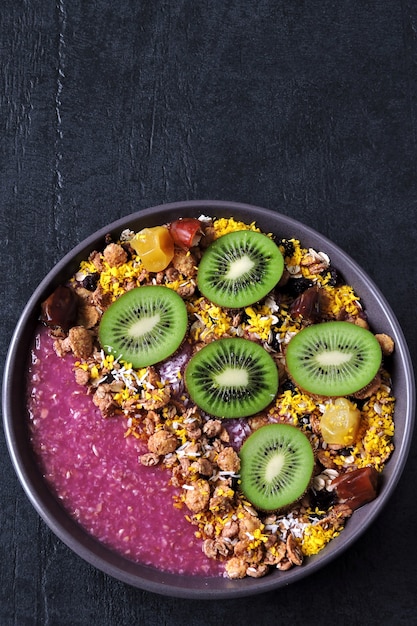 Ontbijtkom met acai smoothie, havermout, granola en fruit.