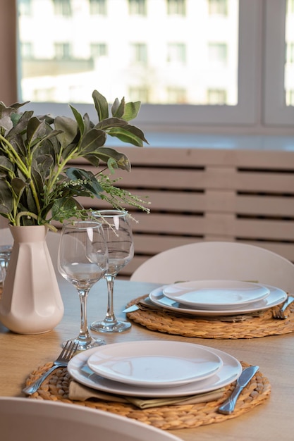 Ontbijtopstelling op houten tafel met mooie vaas en moderne stoel. Een gedekte tafel voor twee personen.