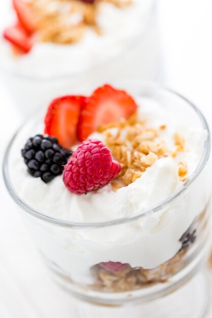 Ontbijtparfait gemaakt van Griekse yoghurt en granola met daarop verse bessen.