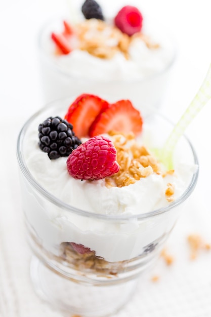 Foto ontbijtparfait gemaakt van griekse yoghurt en granola met daarop verse bessen.