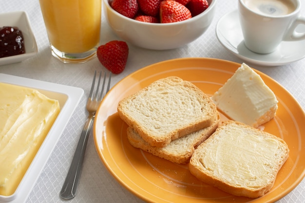 Ontbijttafel met boter, toast, jam en aardbeien.