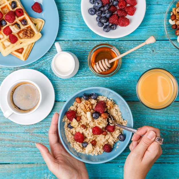 Ontbijttafel met wafels, havermout, ontbijtgranen, koffie, sap en verse bessen. gezond ontbijt