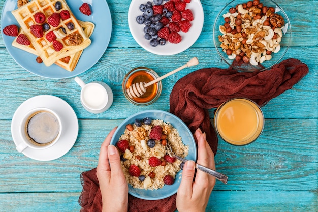 Ontbijttafel met wafels, havermout, ontbijtgranen, koffie, sap en verse bessen