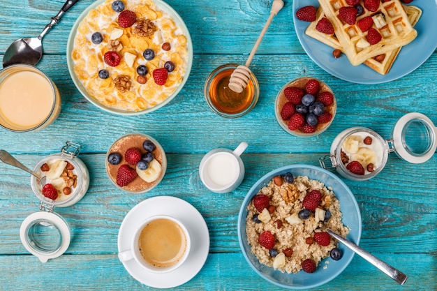 Ontbijttafel met wafels, havermout, ontbijtgranen, koffie, sap en verse bessen