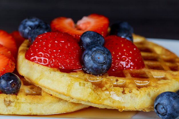 Ontbijtwafel met verse bosbessen, aardbeien en ahornsiroop