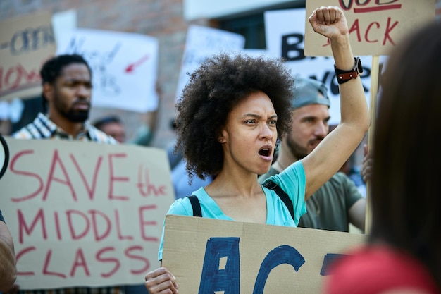 Ontevreden Afro-Amerikaanse vrouw die protesteert met een menigte mensen en schreeuwt met opgeheven vuist