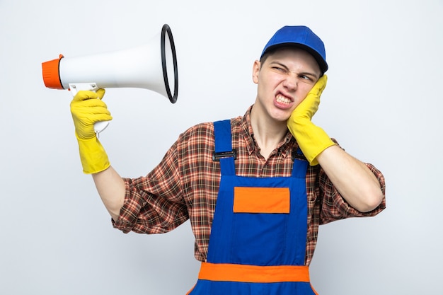 Ontevreden hand op de wang leggen, jonge schoonmaakster met uniform en pet met handschoenen met luidspreker